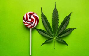 Lollipop pastille next to cannabis leaf